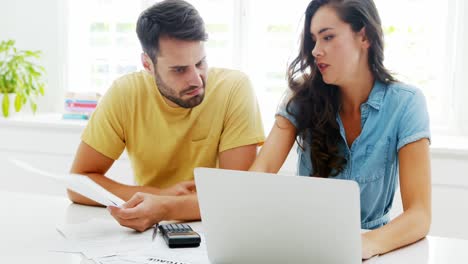 Worried-couple-calculating-their-bills-with-laptop-in-the-kitchen