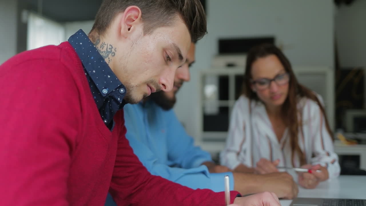 vista lateral de un apuesto hombre tatuado escribiendo en un bloc de notas.