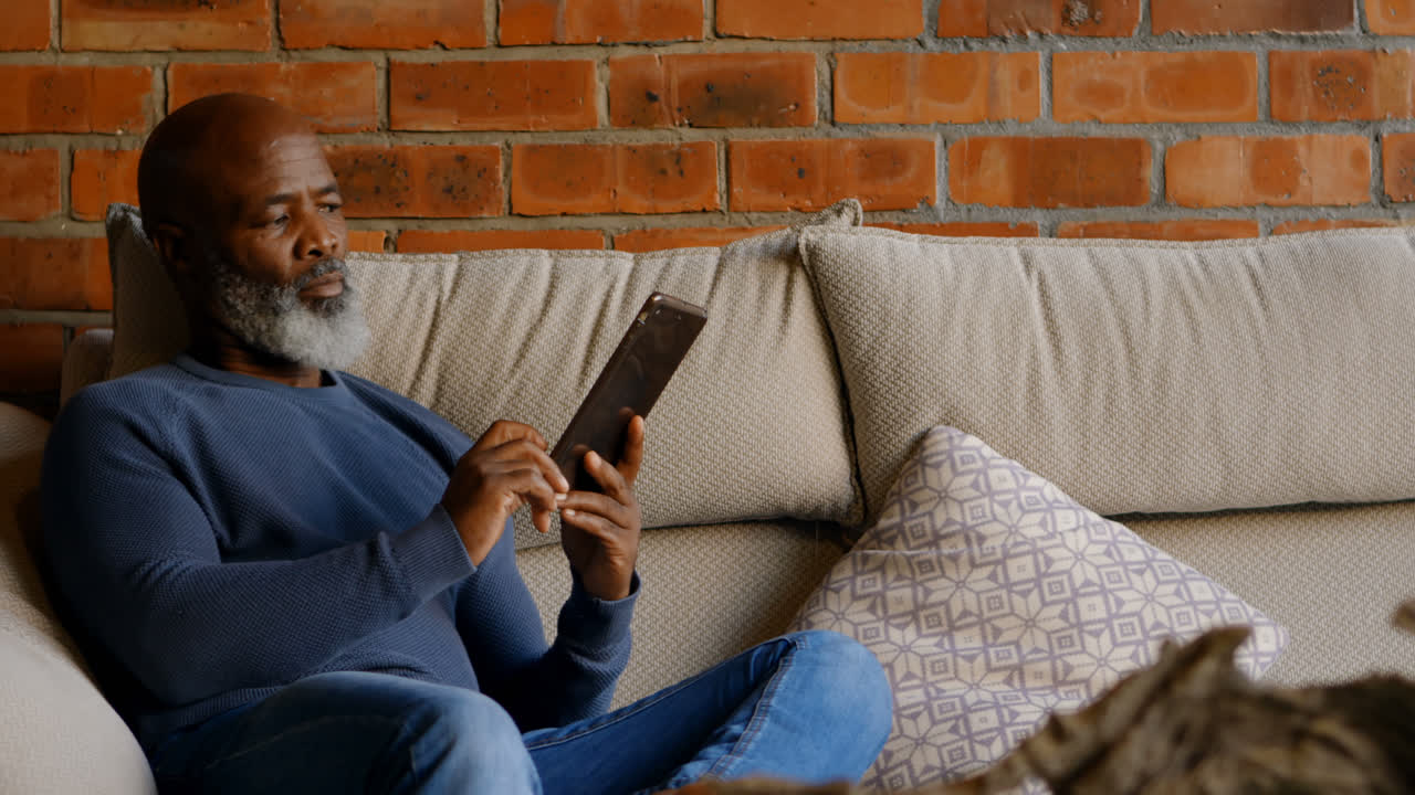 Senior man using digital tablet in living room 4k