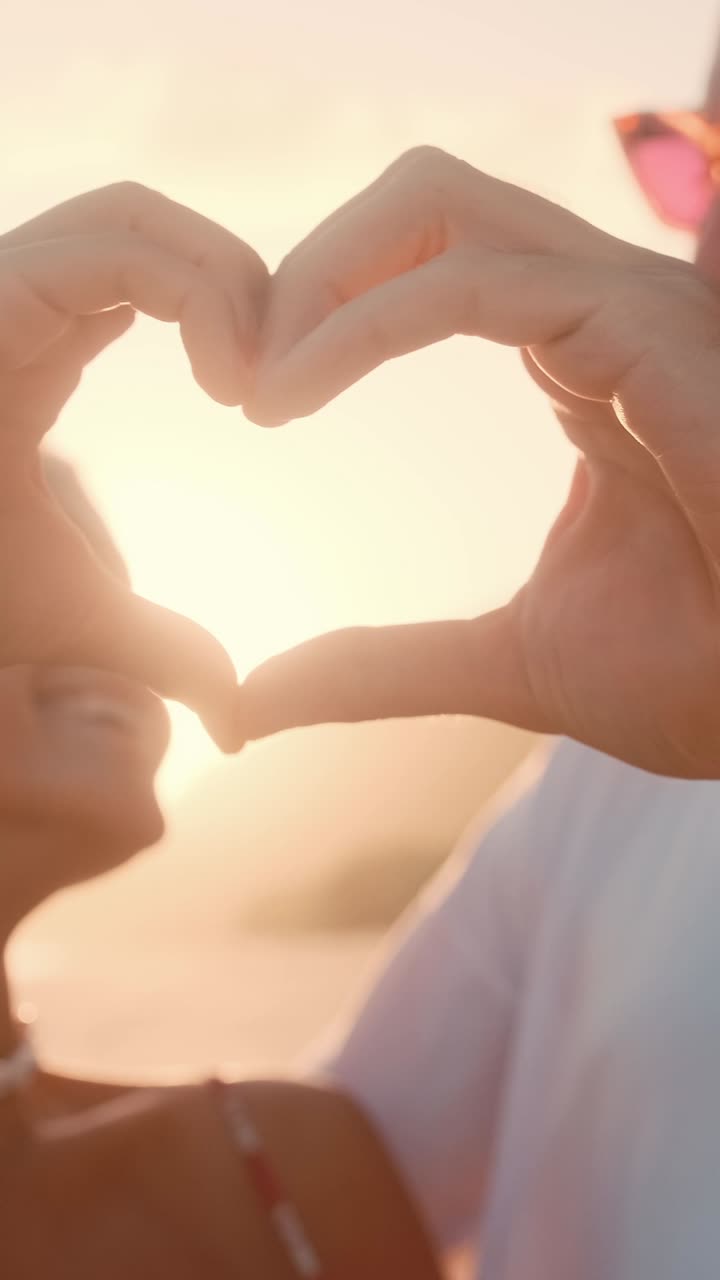 Couple enjoys sunset while making heart shape with hands in nature