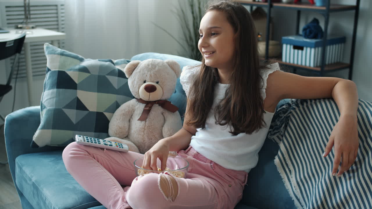 Teenage Girl Watching TV and Eating Popcorn