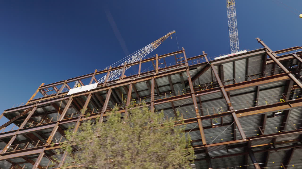 View from moving car of skyscraper under construction in Brooklyn New York City, steel frame high rise building site with cranes, USA