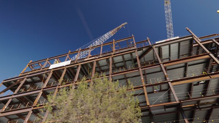 View from moving car of skyscraper under construction in Brooklyn New York City, steel frame high rise building site with cranes, USA