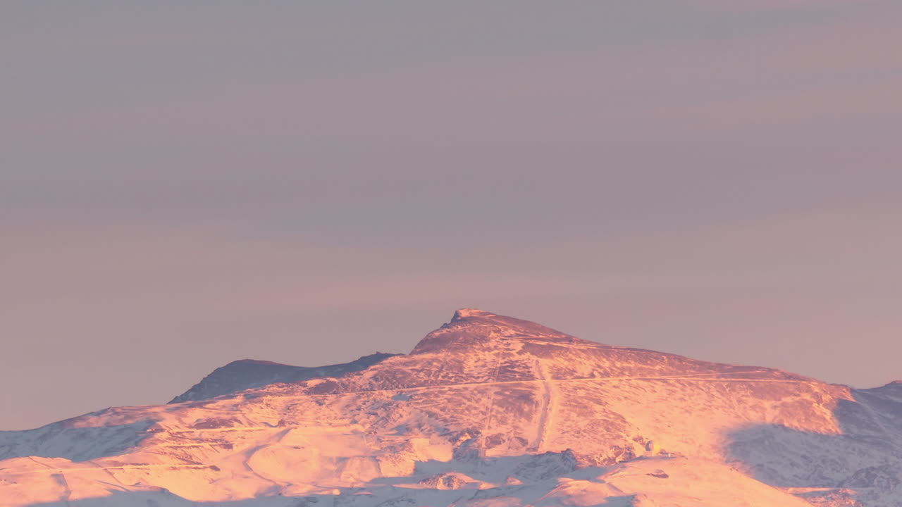Lumihuippuinen Sierra Nevada Veleta -huippu Granadassa, Andalusiassa, Espanjassa auringonlaskun aikaviivekuvauksessa.