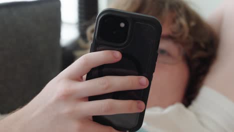 tight shot of young man on phone sitting on a couch, man is out of focus