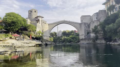 view of mostar bridge on a quiet sunny morning with neretva river flowing by