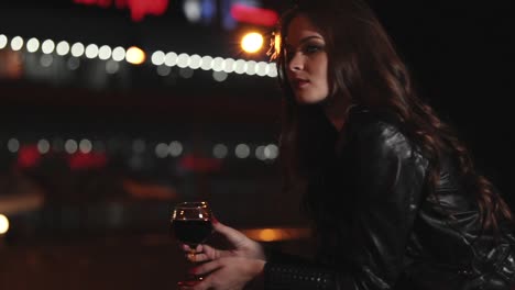 woman with red wine in city at night