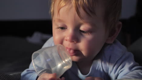 Cute-Baby-Boy-Lying-on-Bed-Playing-with-Plastic-Cup,-Close-Up