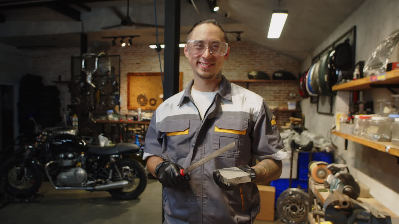 Ritratto di tecnico uomo con pietra per affilare in un garage per moto