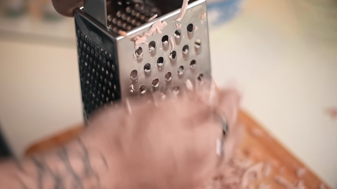 Male hands with tattoo rubbing sausage on a grater. Slow motion