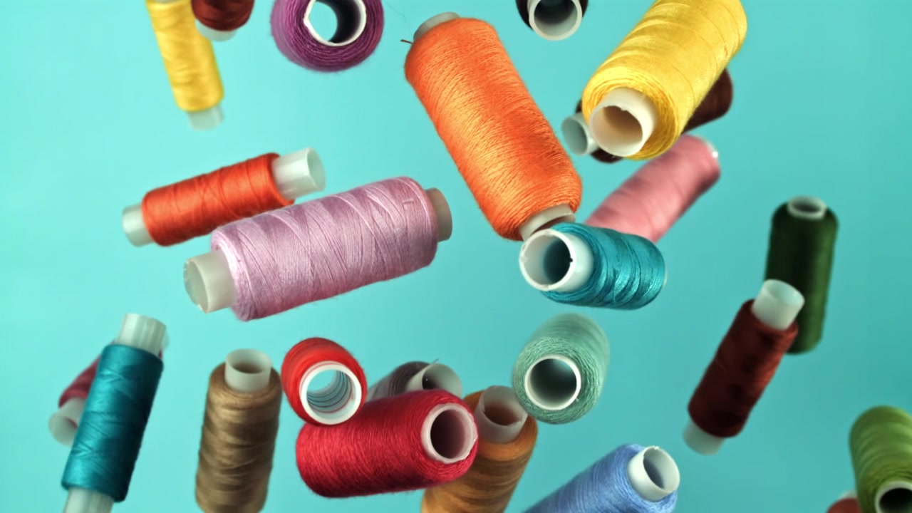 Colorful Thread Spools Falling Against a Blue Background