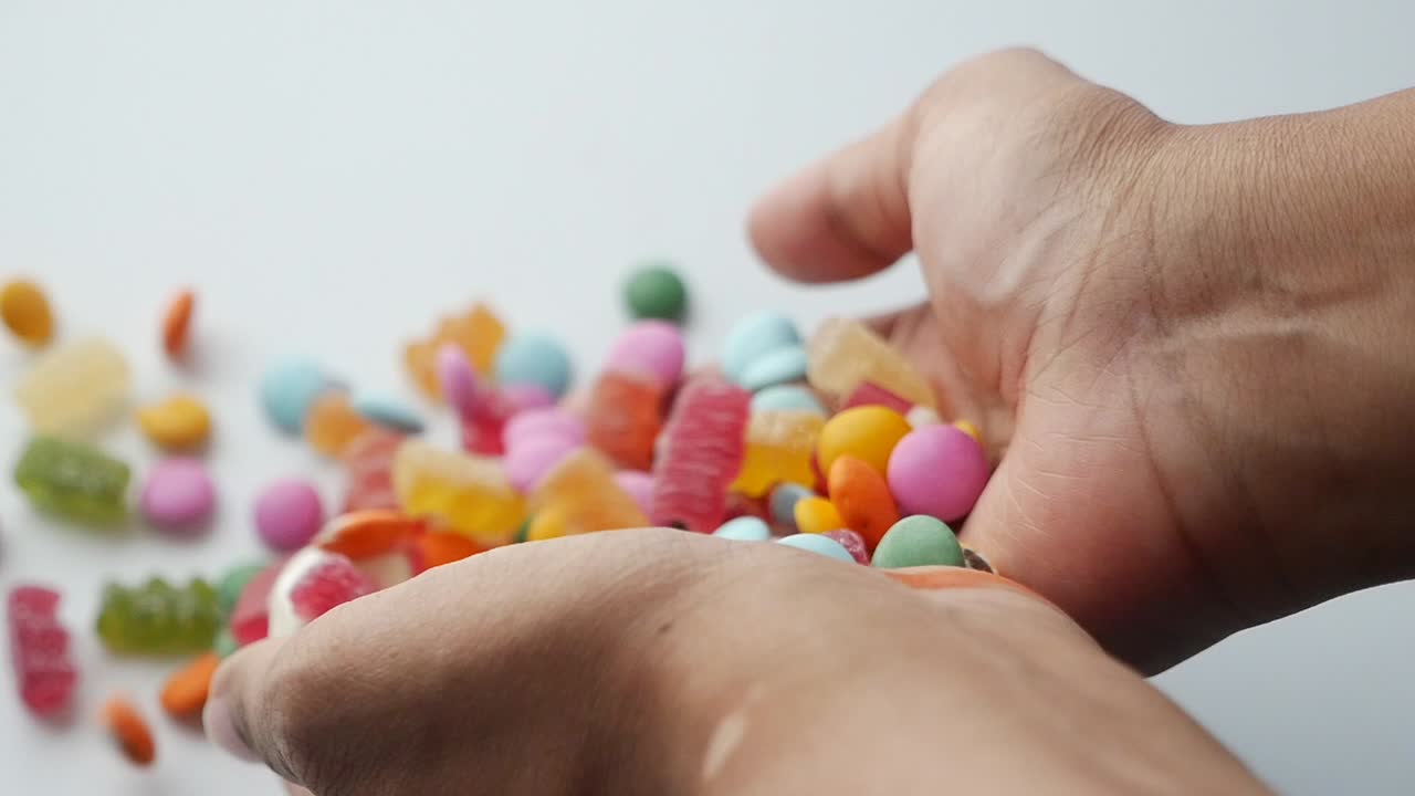 manos con caramelos de colores