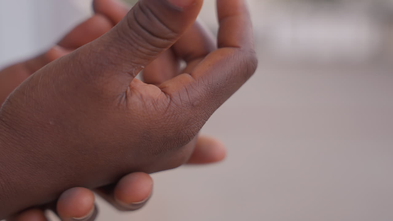 closeup black hands showing dry skin, gentle rubbing and inspection, peeling patches on knuckles, natural light, neutral background, adult black person performing calm selfcare routine, focus