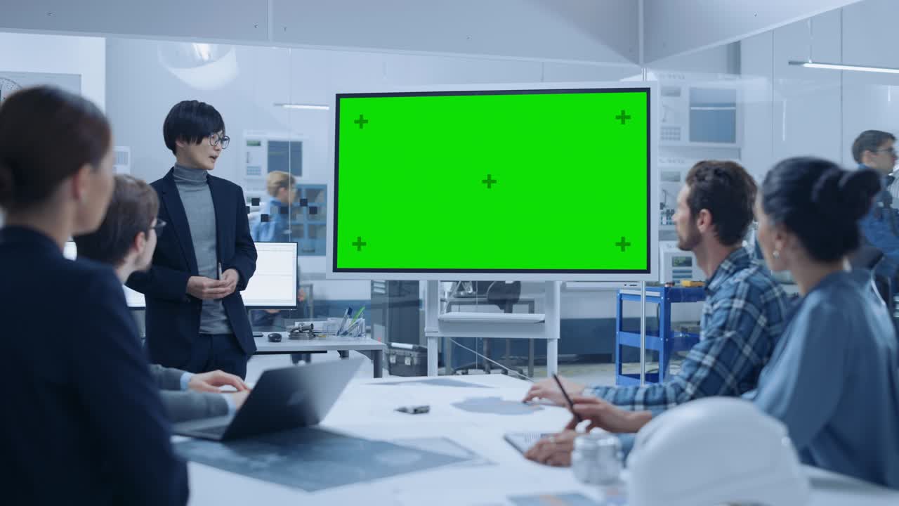 현대 산업 공장 회의: 자신감있는 아시아 엔지니어가 인터랙티브 녹색 모형 화면 화이트 보드를 사용하여 엔지니어, 관리자 그룹에 보고합니다.