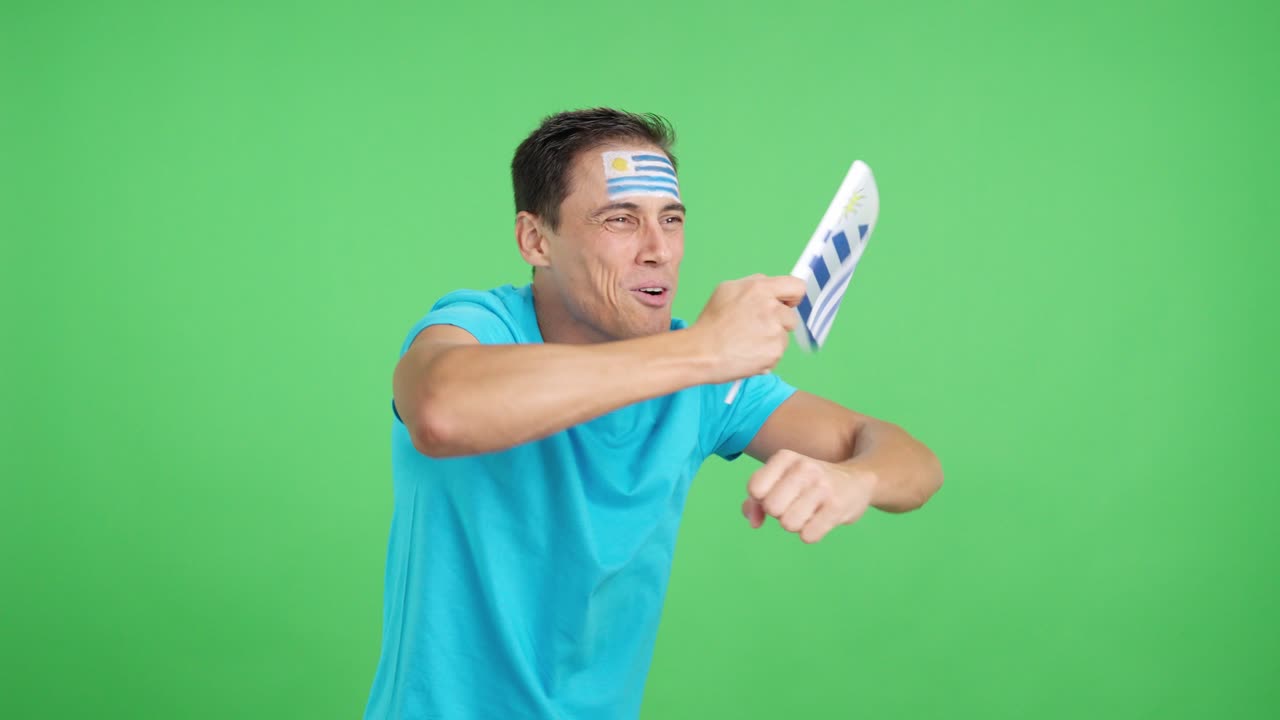Man cheering for Uruguay waving a national flag looking away