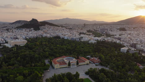Zappeion Hall in National Garden of Athens during sunrise with Lycabettus hill in background, Athens, Drone shot, Panoramic view