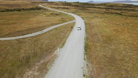 fast, white car on scenic dirt road within dry plains