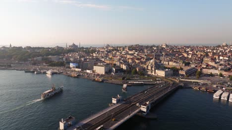 forward drone shot above galata bridge - golden horn at sunrise