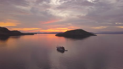 charter yacht anchored in calm water near islands during a stunning red sunset