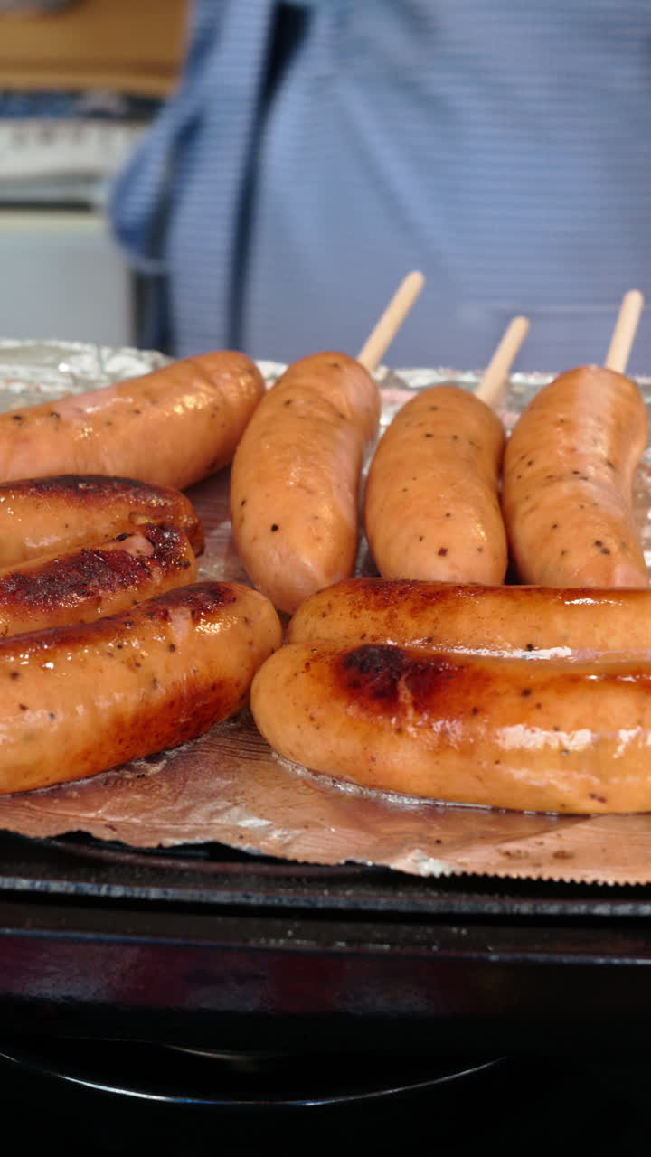 Close up of sausages on skewers flying at the Tsukiji Fish Market in Japan. Vertical