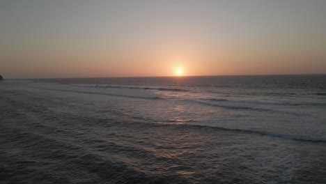 aerial view across the sands of barriga beach towards the atlantic ocean during a beautiful orange sunset