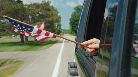 mano con la bandera de estados unidos en un concepto de escandinavia de viaje de ventana de coche