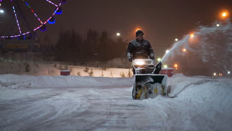 man removing snow at night with snow blower