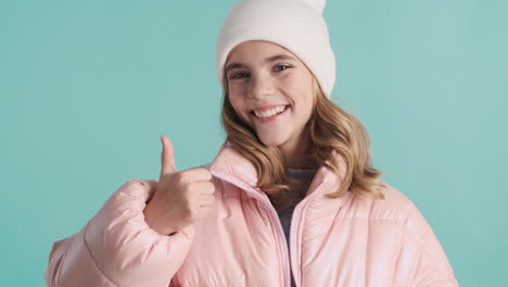 Teenage-Caucasian-girl-with-winter-clothes-and-thumbs-up-in-front-of-the-camera.