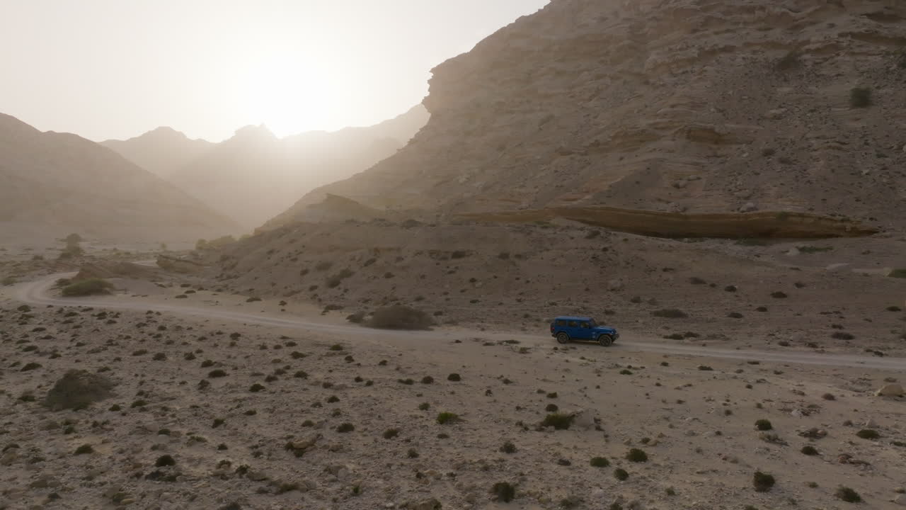 Oman desert landscape with a vehicle driving through a Wadi near the coast