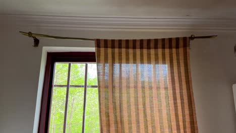 scenic view of a cotton zebra curtain in a village in country side in middle east handmade textile cloth with wooden rod covers the window landscape of green forest mountain cab in village life moka