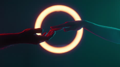 hands reaching through a glowing neon ring