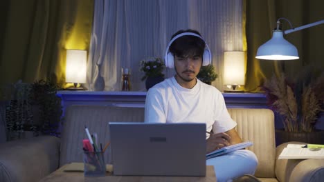 male student listening to music and studying at night.