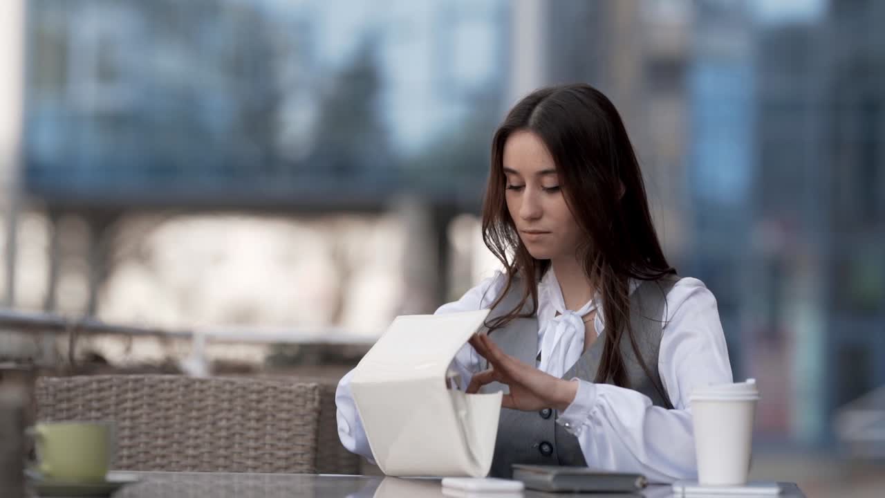 Joven mujer de negocios sentada en la terraza de verano de un café cuenta dinero