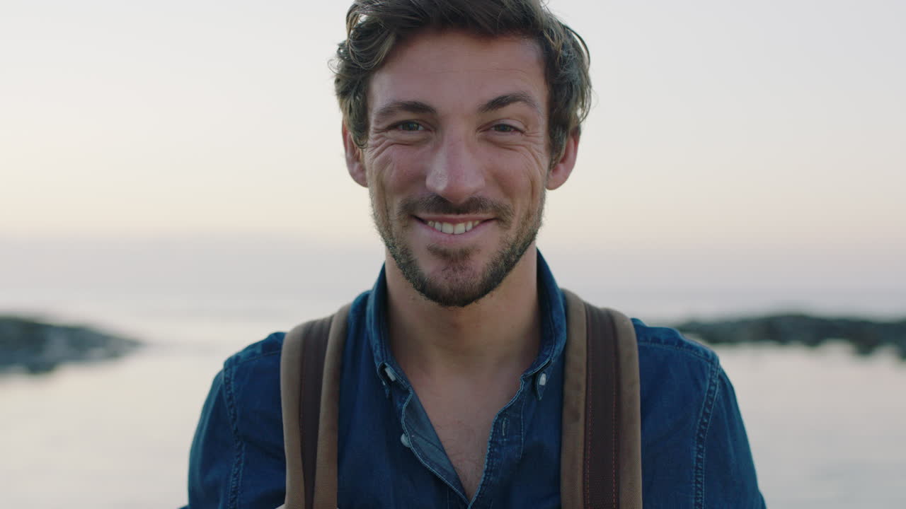 portrait of attractive charming caucasian man smiling cheerful making faces on seaside beach