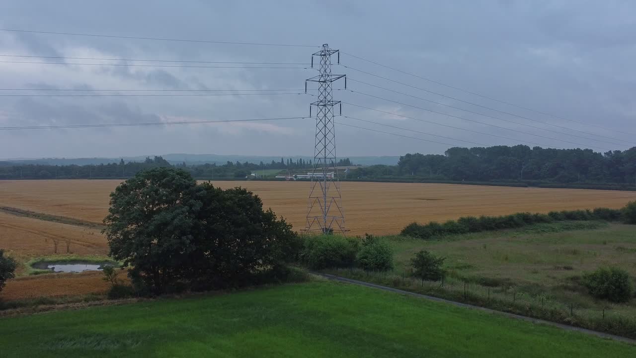 Electricity steel pylon high voltage wires in countryside agricultural farm field aerial view early morning low orbit slow left