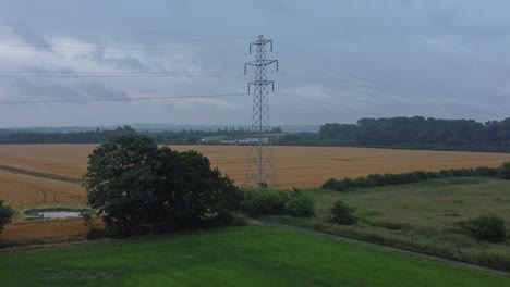 electricity steel pylon high voltage wires in countryside agricultural farm field aerial view early morning low orbit slow left