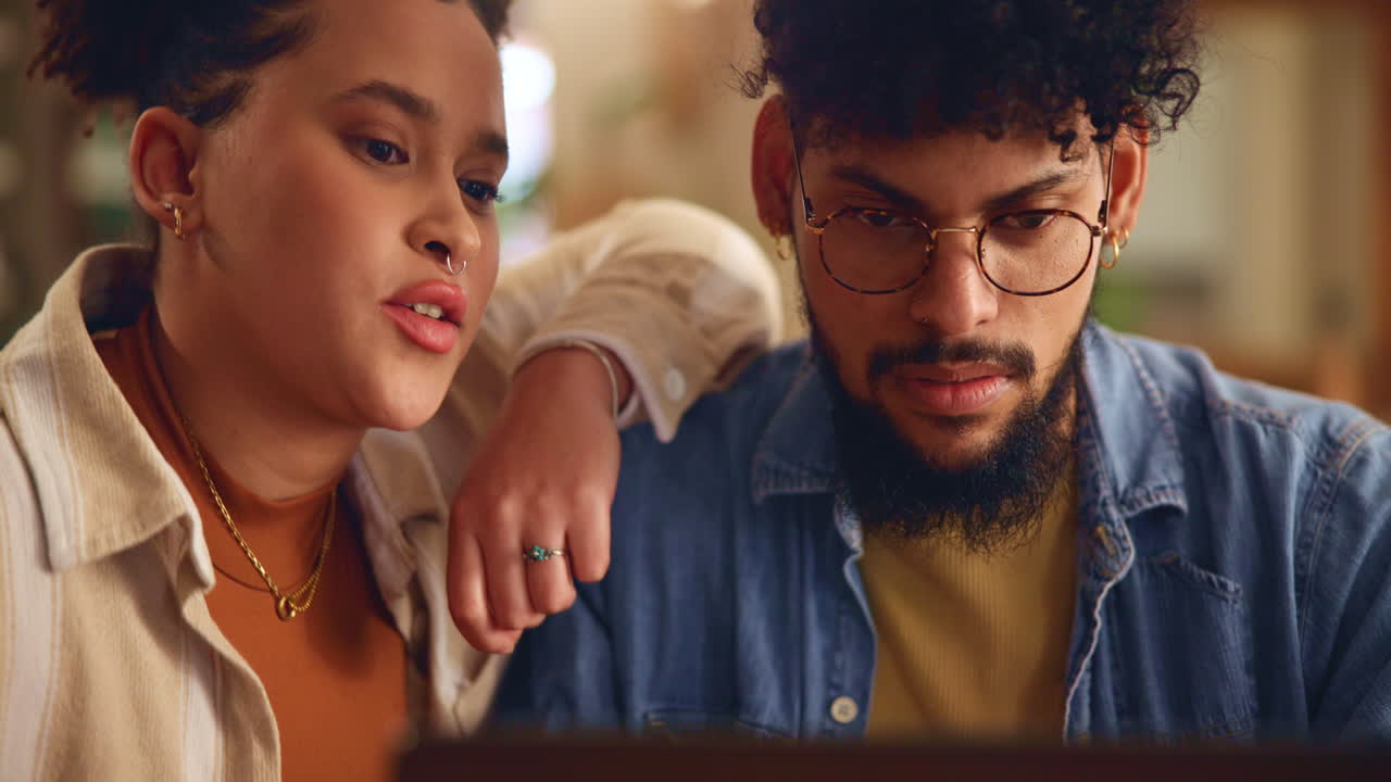 una pareja joven trabajando juntos en una computadora portátil en casa.