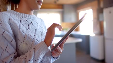 happy african american woman using tablet in sunny kitchen, in slow motion