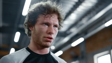 tired kickboxer standing after training at gym. sportsman making break