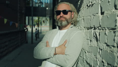 man leaning on a brick wall in urban setting