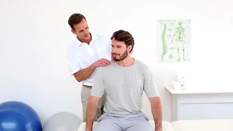 physiotherapist touching patients injured shoulder