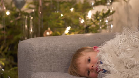 sleepy baby boy resting on couch, christmas holidays