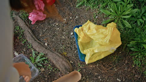 woman hand picking trash at park cleanup closeup. volunteer collecting litter