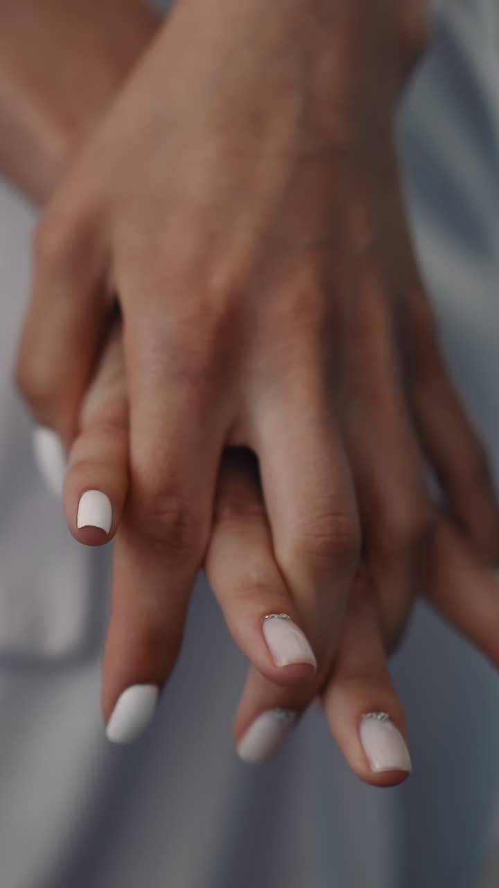 Woman with white manicure does gymnastics for fingers in room closeup slow motion. Lady removes tense in hands after work. Body relaxing exercise