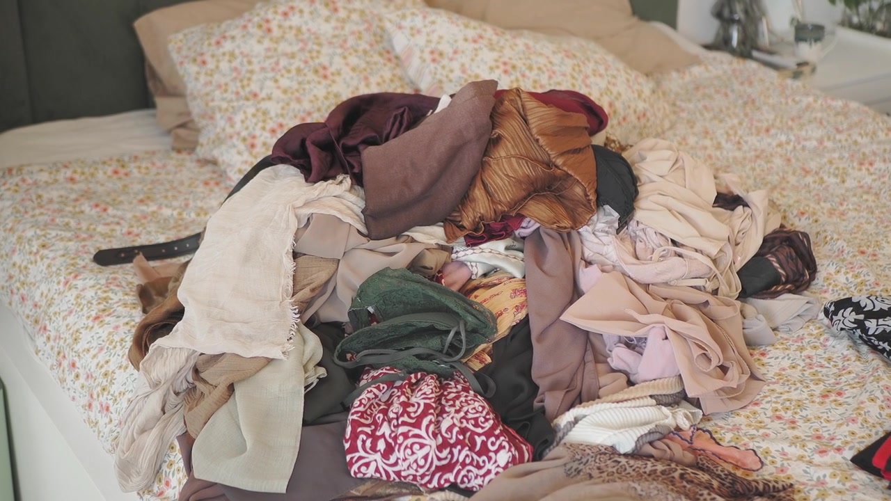Large Pile of Unorganized Clothing on a Bed