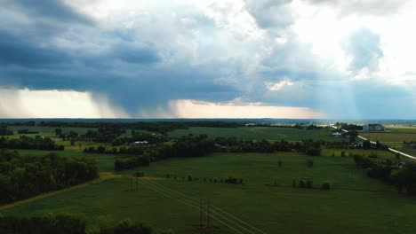 rising-aerial-Appleton,-Wisconsin-farmland-rays-of-sunshine-through-ominous-rain-clouds-storm-in-distance