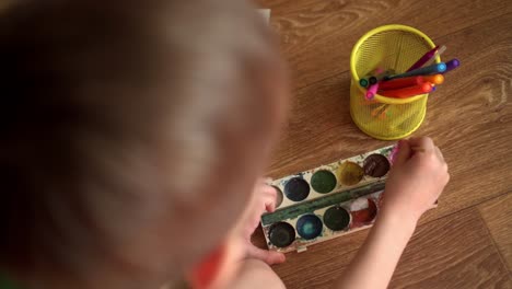 a child on the floor draws a drawing with watercolors 04