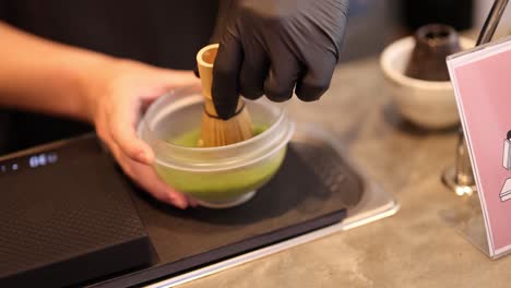 hands whisk matcha in a bowl with precision, under warm lighting, highlighting traditional tea-making techniques