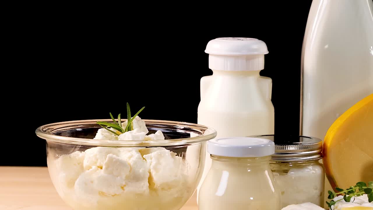 A variety of dairy items including milk, cheese, and yogurt displayed against a black backdrop.