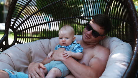 Dad holding his tiny baby son and kisses him on the head. Father having rest outdoors with his infant child.